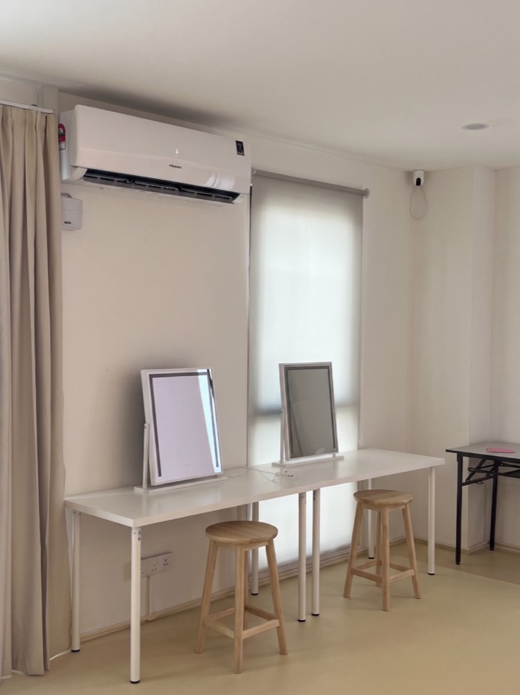 Makeup area with a long white table, two mirrors and wooden stools