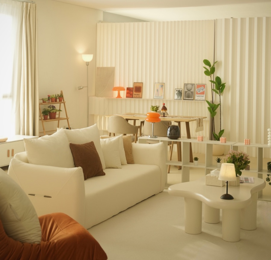 The living area with a cream sofa, cloud coffee table and an orange lounge chair