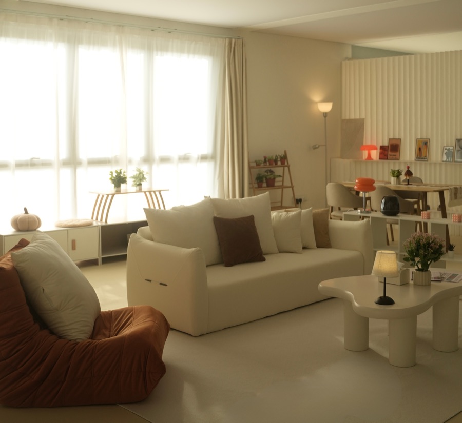 The full room in warm evening light with a floor lamp and sheer curtains