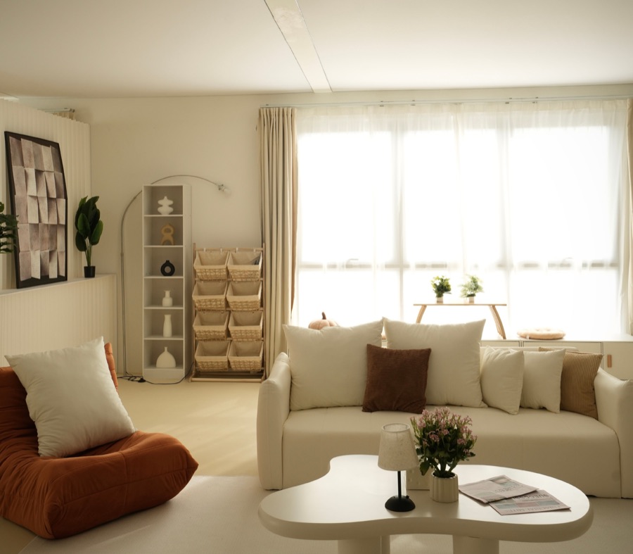 Cream sofa and orange lounge chair beside sheer curtains