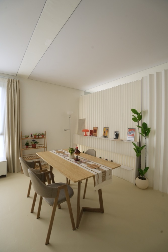 Oak dining table and chairs in front of the fluted wall and shelf of prints